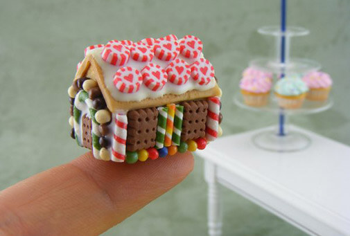 a tiny gingerbread house on a person’s fingertip