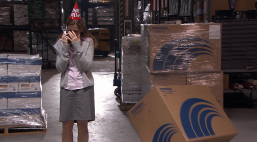 Pam laughing on the phone while a cardboard box tips over