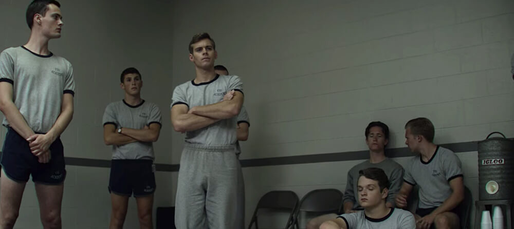 a group of guys at a gym, a vintage metal Igloo coolor off to the side