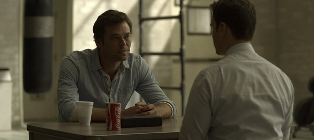 Holden interviews an inmate and can of Coke sits on the table