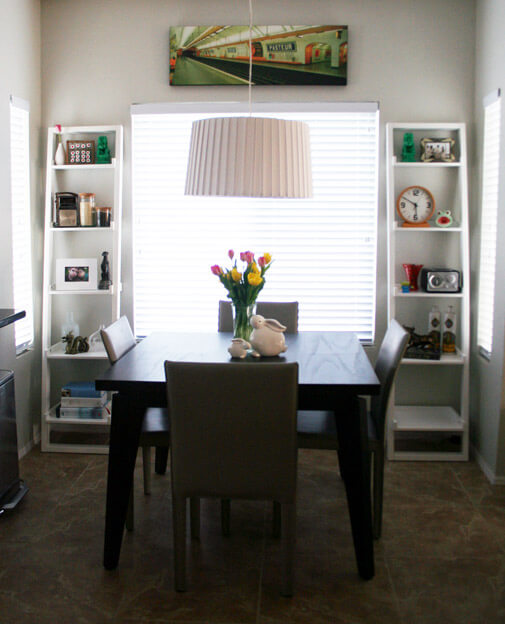 same dining room with two styled ladder shelves on each side of the window and a Paris petro print above