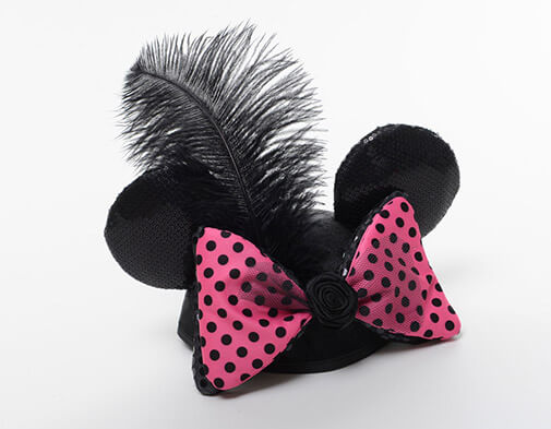 ear hat with a big statement feather and pink and black polka dot bow