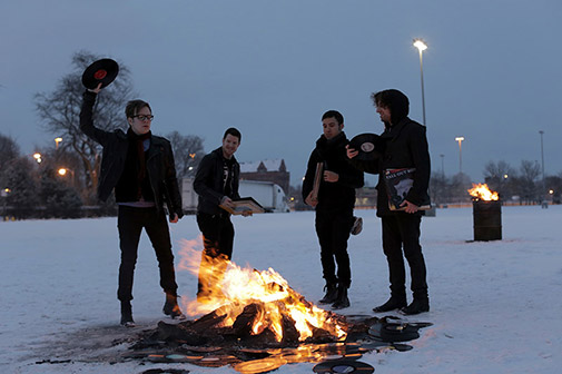 Fall Out Boy in the snow, throwing vinyl records onto a bonfire