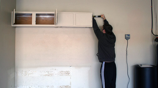 Clay prying the cabinet off the wall