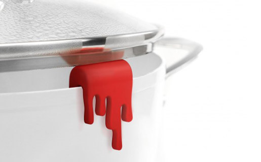 a silicone splatter of red sauce that holds up a pot lid