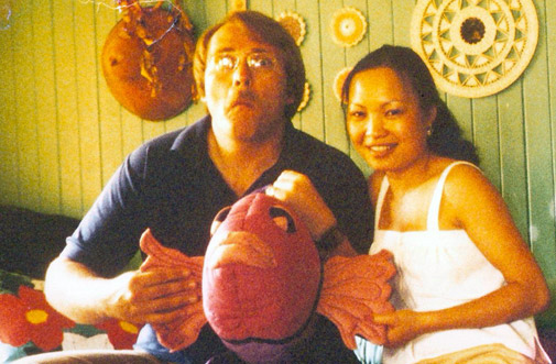 vintage photo of my parents, my dad making the same face as the fish plush he is holding