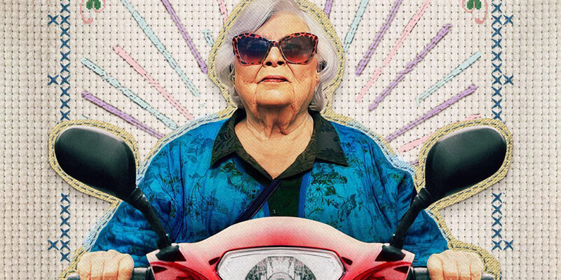 June Squibb wearing sunglasses and riding on a scooter