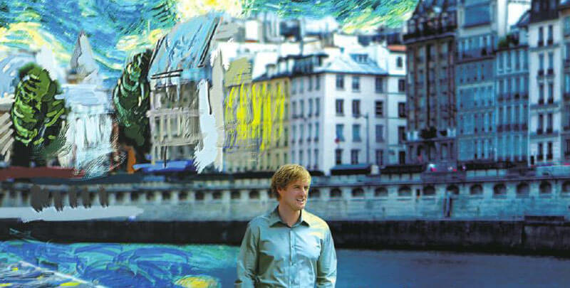 Owen Wilson walks in front of a painted Paris streetscape