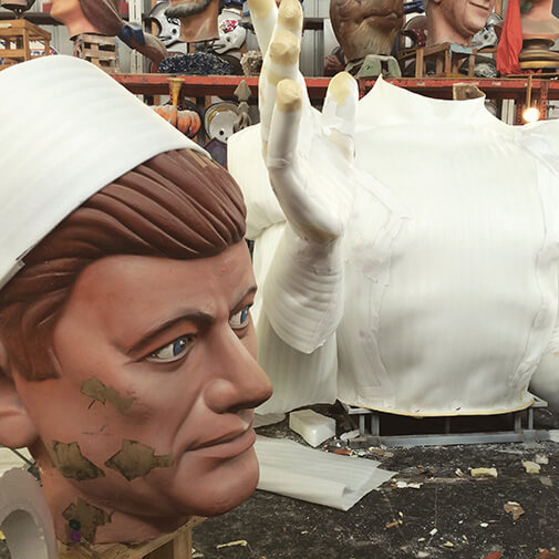 pieces of a giant parade float of a man, the head sitting next to the torso