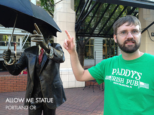 Clay pointing next to the Allow Me Statue in Portland