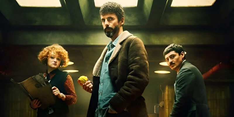 Matthew Goode, Alexej Manvelov, and Leah Byrne as detectives in their basement office